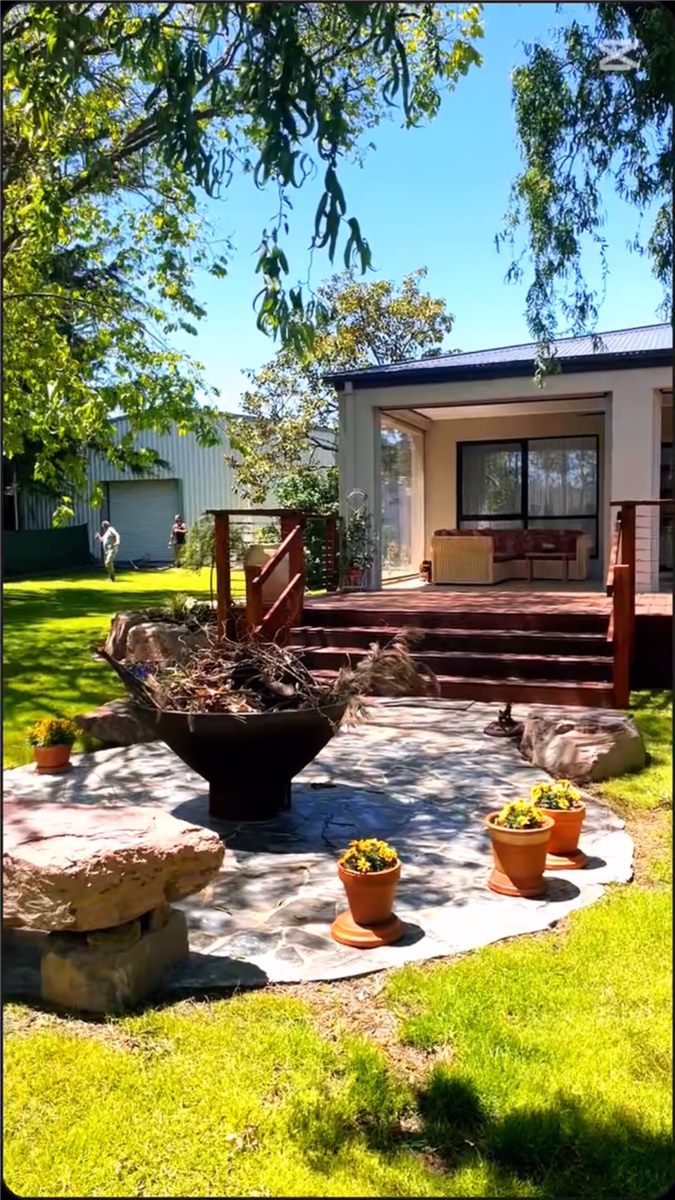 Finished fire pit entertaining area with crazy paving, timber deck and landscaped lawn by Sunnybank Horticultural